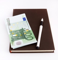 Euro banknotes, notebook and pen