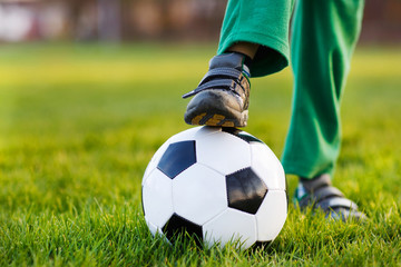 Obraz premium Feet of little boy with football on football field, outdoors