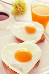 Fototapeta premium heart-shaped fried eggs, bread and orange juice