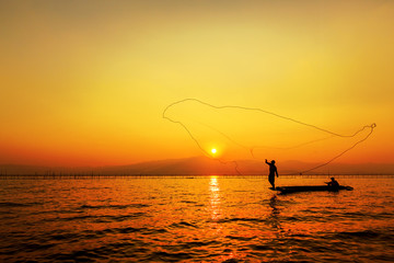 throwing fishing net during sunset , thai