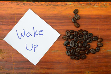 coffee beans and wake up note on the wooden background