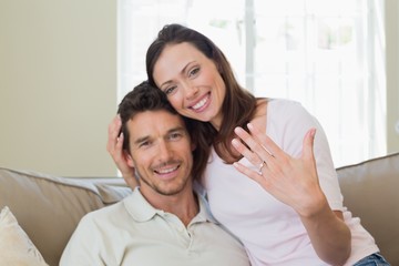 Obraz na płótnie Canvas Happy woman showing engagement ring besides man
