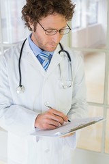 Serious male doctor writing reports in hospital