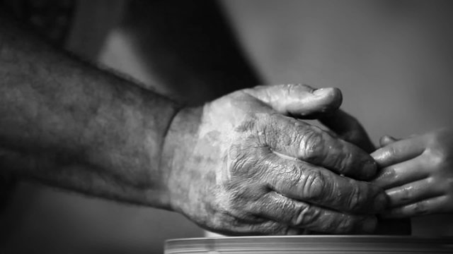 Hands of old potter and young follower
