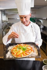 Confident male chef holding cooked food in kitchen