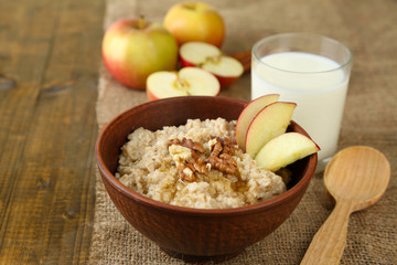 Tasty oatmeal with nuts and apples on wooden table