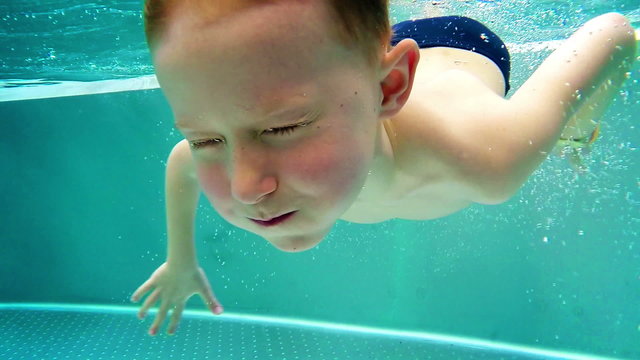 Slowmotion: Playfull boy dives in hot winter pool