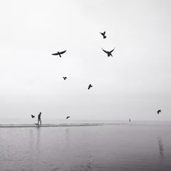 Tuinposter man walking on the beach with flock of birds © nasruleffendy