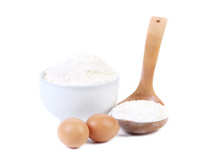 Spoon and bowl with flour two eggs.
