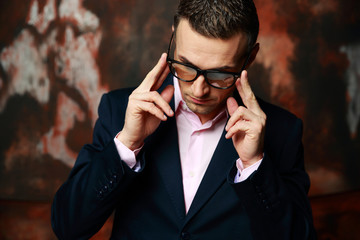 Cool fashion man in glasses standing over industrial background