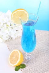 Glass of cocktail on table on light blue background