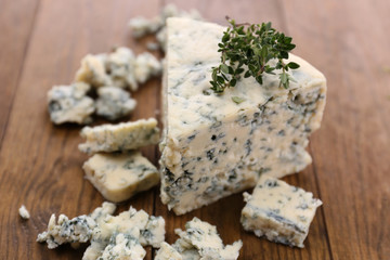 Tasty blue cheese with thyme, on wooden table