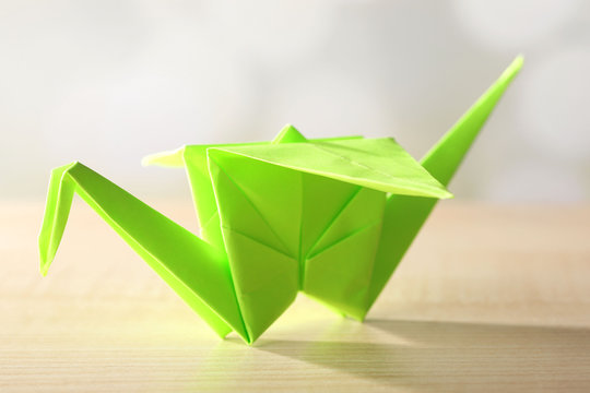 Origami crane on wooden table, on light background