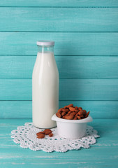 Almond milk in bottle with almonds in bowl,