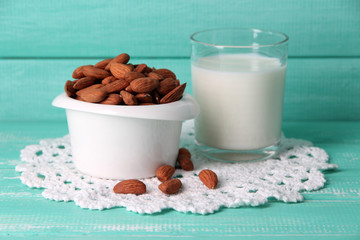 Almond milk in glass with almonds in bowl,