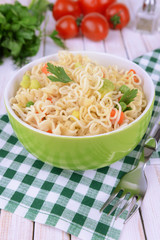 Tasty instant noodles with vegetables in bowl on table close-up