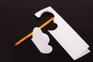 Paper cut out butterfly and pencil, on wooden background