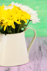 Beautiful chrysanthemum flowers in pitcher on wooden table