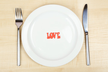 Plate with inscription love on wooden table close-up