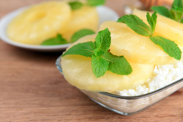 Bowl of tasty cottage cheese with pineapple on wooden table