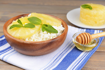 Bowl of tasty cottage cheese with pineapple on wooden table