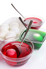 Eggs with liquid colour in glass bowls isolated on white