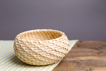 Empty wicker basket on wooden table, on dark background