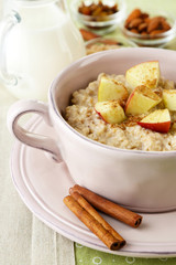 Tasty oatmeal with apples and cinnamon on table close up