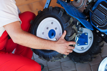 Man mounting tyre on a gasoline motor  tiller
