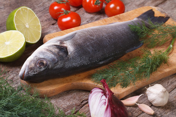 Fresh raw fish sea bass on a cutting board with vegetables