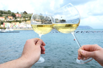 Two wineglasses in the hands against the harbour of Portvenere,