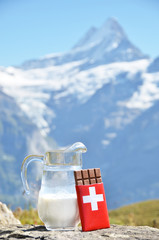Swiss chocolate and jug of milk against mountain peak. Switzerla