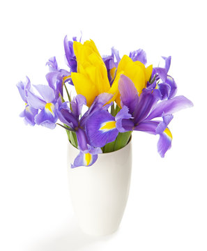 Irises and tulips in the white vase isolated on white.
