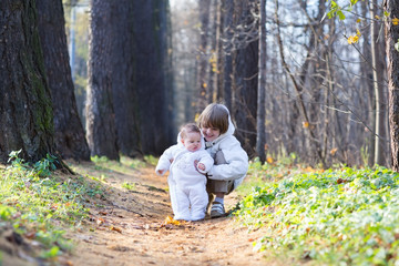 Fototapeta premium Boy playing with his baby sister in the park on a cold day