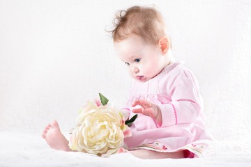 Funny baby girl playing with a big flower