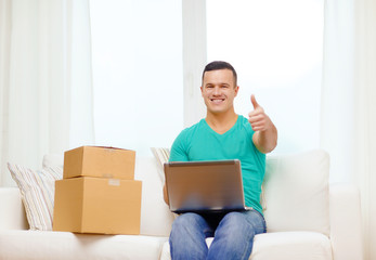 man with laptop and cardboard boxes at home