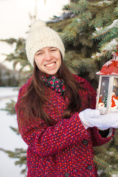 Young beautiful woman with red Christmas lantern in the snow