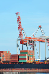 Fototapeta premium Container stack and ship under crane bridge