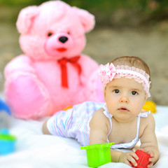 Sweet baby girl with teddybear the background outdoors