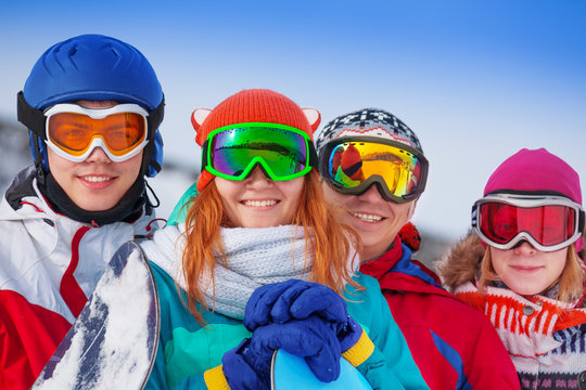 Four happy snowboarders wearing goggles