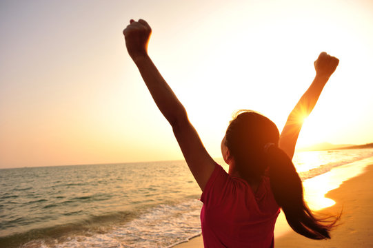 cheering woman hiker open arms at sunrise seaside 
