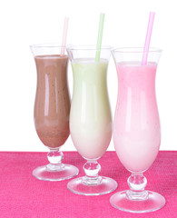 Milk shakes with fruits on table on white background