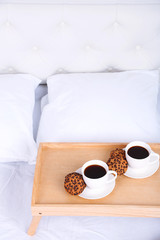Cups of coffee on comfortable soft bed with pillows