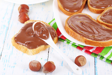Bread with sweet chocolate hazelnut spread on plate on table