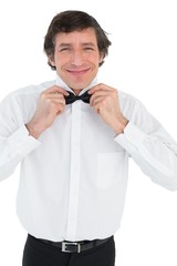 Smiling groom adjusting bow tie