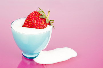 Strawberry in blue cup with yogurt spill