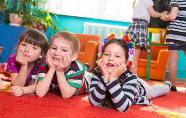Three children lying on floor with hands under cheeks