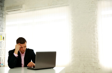 Confident businessman sitting at the table with laptop in office