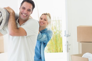 Fototapeta premium Couple carrying rolled rug after moving in a house