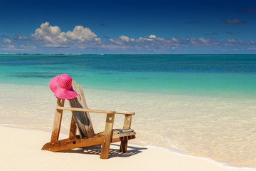 Beach chairs with pink hat  on white sandy beach